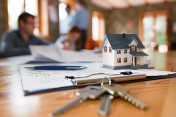 Image of a title closing for a residential house with keys and title paperwork in the foreground